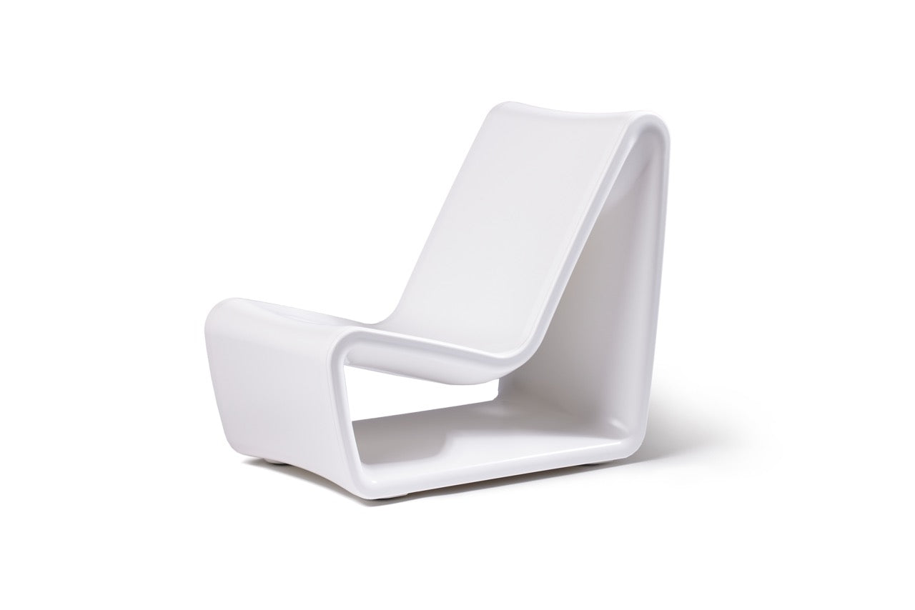 Modern white concrete outdoor lounge chair with molded armrest and contoured backrest for poolside or patio use
